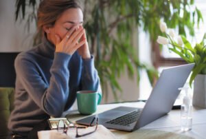Caucasian young woman frustrated sitting at table with laptop